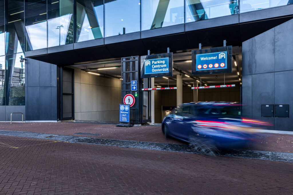 Blauwe peugot die de parkeergarage van ODE in Amsterdam in rijd